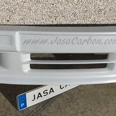 Para-choques dianteiro branco com texto gravado sobre superfície em cimento