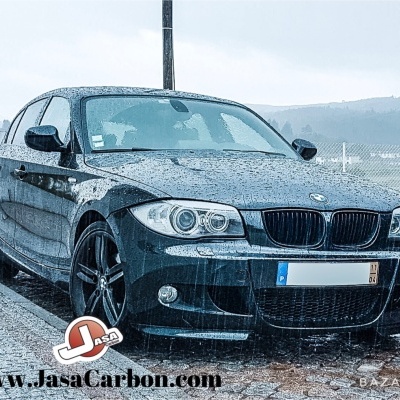 Carro BMW preto com jantes pretas em superfície de pedra molhada, placa portuguesa
