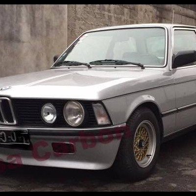 Carro clássico BMW cinzento com faróis redondos e jantes douradas