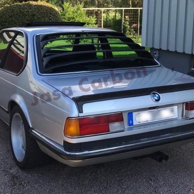 Carro BMW clássico cinza prateado com jantes brancas e persianas pretas nas janelas traseiras