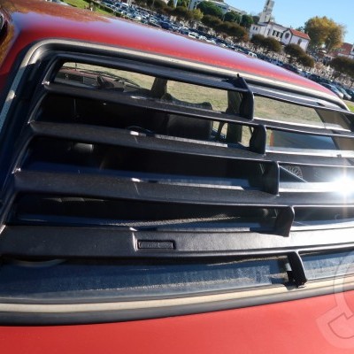 Carro vermelho com persiana preta na janela traseira ao ar livre