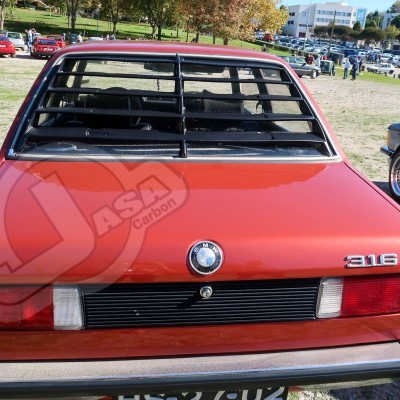 Traseira de carro BMW 316 vermelho com persianas pretas no vidro em parque