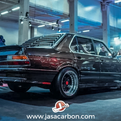 Carro desportivo clássico preto em evento interior com luzes azuis e rosas