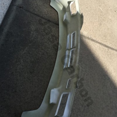 Parachoques de automóvel plástico branco no chão de cimento