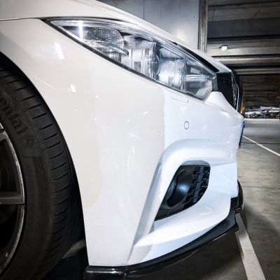 Parte frontal esquerda de carro branco com farol e pneu preto