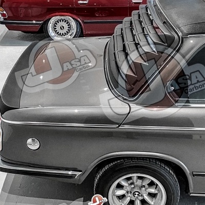 Carro clássico cinza com persiana traseira e tejadilho preto, ao lado de carro vermelho em parque