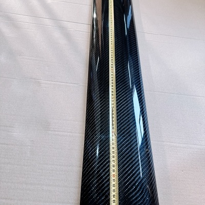 Peça em fibra de carbono preta com padrão texturizado e fita métrica a medir comprimento