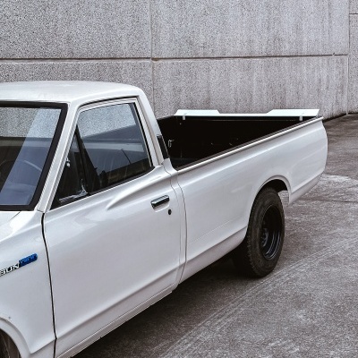 Camião pick-up branco com pneus pretos junto a parede cinza