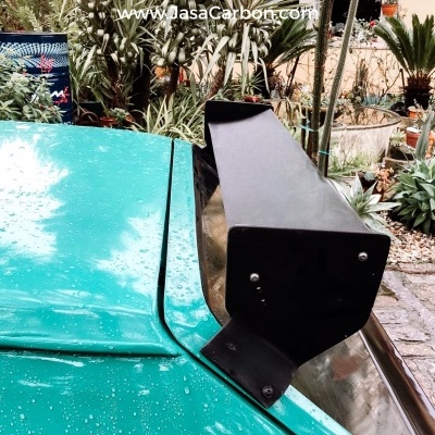 Asa traseira preta num carro verde com gotas de água e logo Jasa