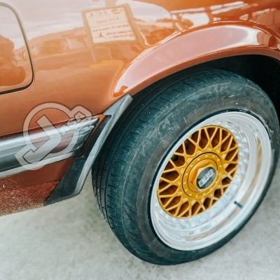 Roda de carro com jante dourada e aro prateado numa carroçaria castanha