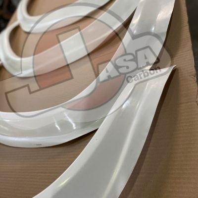 Peças brancas curvas em fibra de vidro ou plástico sobre papelão com logótipo ASA Carbon ao fundo