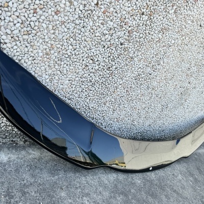 Pára-choques frontal preto brilhante encostado na parede texturada branca