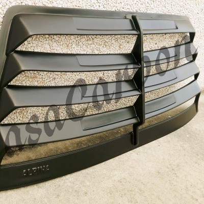 Grelha frontal preta texturizada colocada junto a uma parede clara