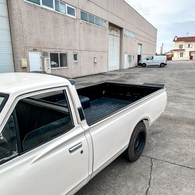 Carrinha pickup branca em zona industrial com edifícios comerciais ao fundo