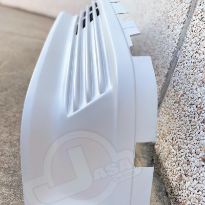 Carcaça branca de plástico com aberturas para ventilação junto a uma parede granulada