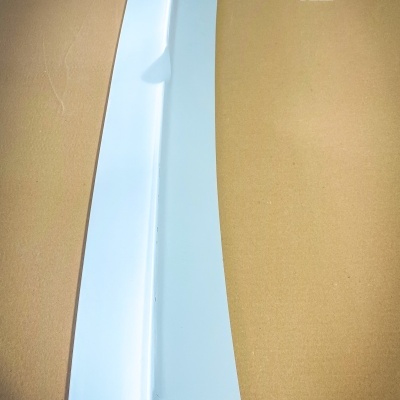 Peça de carro branca sobre superfície castanha com texto BMW E30 XL