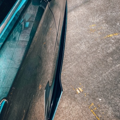 Automóvel preto estacionado com acessório aerodinâmico preto na porta junto ao chão