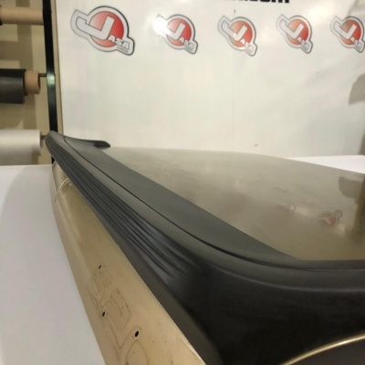 Objeto retangular bege com superfície preta, texto Jasacarbon.com ao fundo