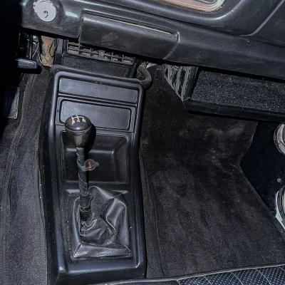 Alavanca de mudanças manual com padrão de velocidades 1-5 e marcha atrás em carro com interior preto e banco azul