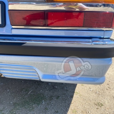 Traseira de carro azul claro com pára-choques preto e luzes traseiras vermelho, branco e laranja, placa 61 e autocolante JASA