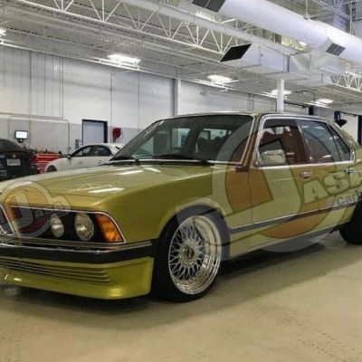 Carro clássico BMW verde-oliva com jantes prateadas em garagem