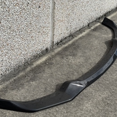 Spoiler dianteiro preto de fibra de carbono com fita azul no chão