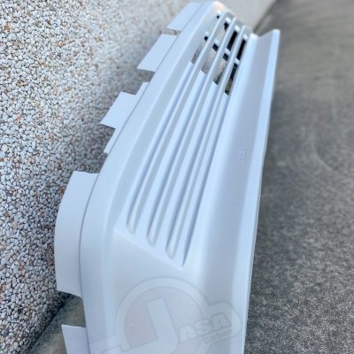 Para-choques dianteiro branco para automóvel com entradas de ventilação em relevo encostado a parede