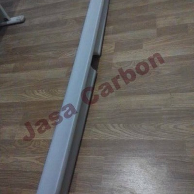 Peça cinza claro longa sobre chão de madeira com texto 'Jasa Carbon'