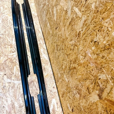 Dois perfis metálicos pretos sobre madeira aglomerada