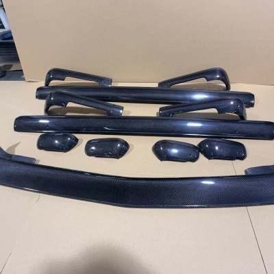 Peças automóveis em fibra de carbono sobre superfície castanha contra fundo de oficina