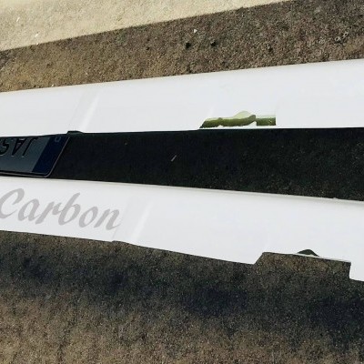 Peças de carroceria preta e branca com texto JasaCarbon colocadas no pavimento