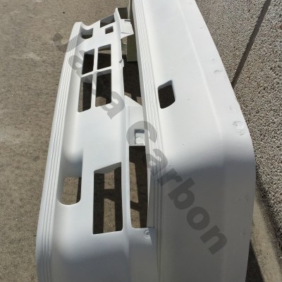 Peças brancas de plástico para automóvel apoiadas no chão ao lado de parede