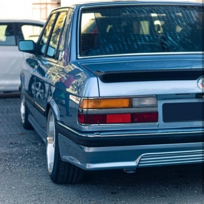 Carro cinzento metálico visto de trás com faróis traseiros e jantes prata.