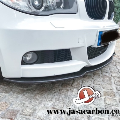 Parte dianteira inferior de carro branco com divisor frontal de fibra de carbono e calçada de pedra
