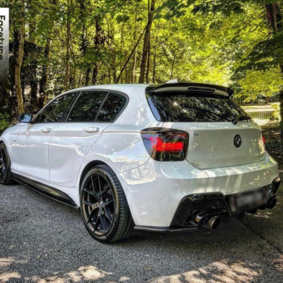 Carro hatchback branco estacionado numa estrada com árvores