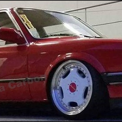 Carro sedan vermelho escuro rebaixado com jantes largas prateadas