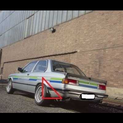 Automóvel cinzento com faixas coloridas estacionado junto a uma parede de tijolos