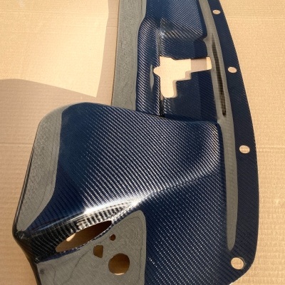 Peça de carbono azul com padrão de fibra e detalhes cinza com buracos de fixação