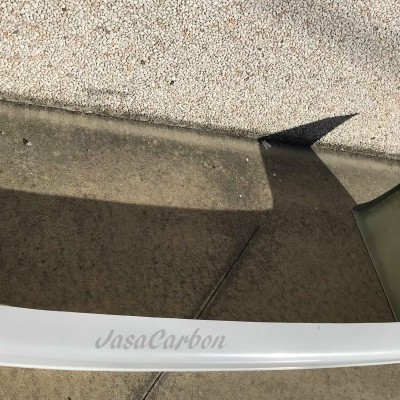 Spoiler traseiro de carro branco com texto 'JasaCarbon' apoiado no chão de cimento