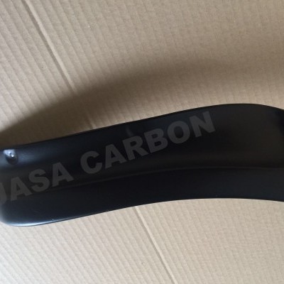 Peça automóvel preta com texto JASA CARBON sobre fundo bege