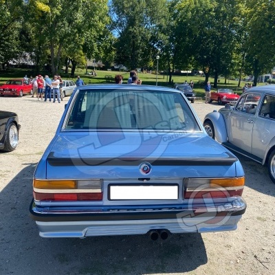 Carro clássico azul metálico visto de trás com farolins retangulares e pára-choques cromados