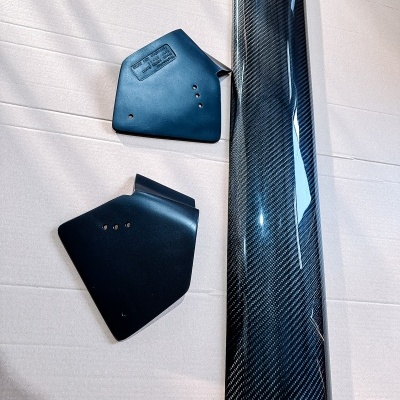 Três peças de fibra de carbono e plástico preto sobre fundo claro.