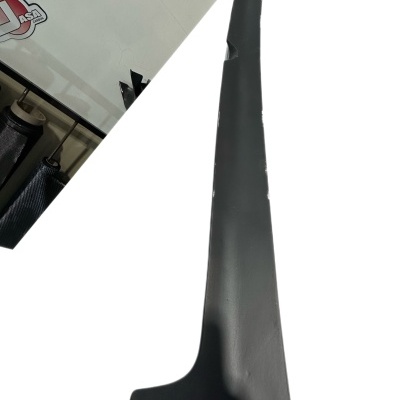 Peça preta alongada de plástico com fundo branco e autocolantes na parede