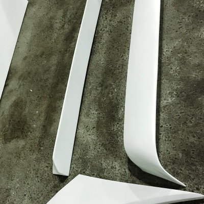 Peças brancas de automóvel em plástico ou fibra sobre chão cinzento áspero