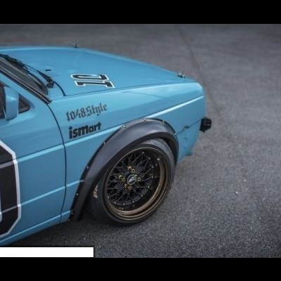 Carro azul claro com guarda-lamas pretos e jantes pretas com aro dourado