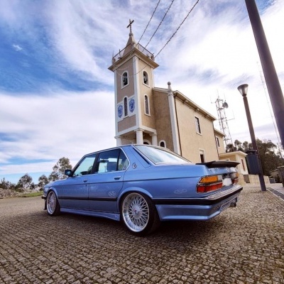 Carro clássico azul estacionado em frente a igreja sob céu nublado