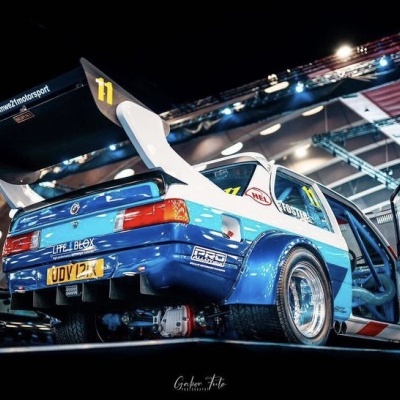 Carro de corrida azul e branco com asa traseira grande e portas abertas