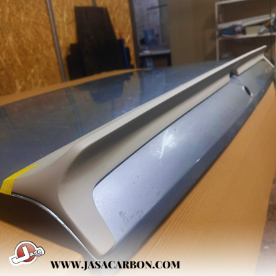 Spoiler traseiro de carro cinza e azul metálico sobre superfície de madeira em oficina