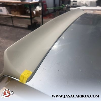 Spoiler automóvel cinza claro na tampa traseira prateada com fita amarela num canto