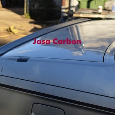 Parte traseira de carro prateado com spoiler e texto Jasa Carbon